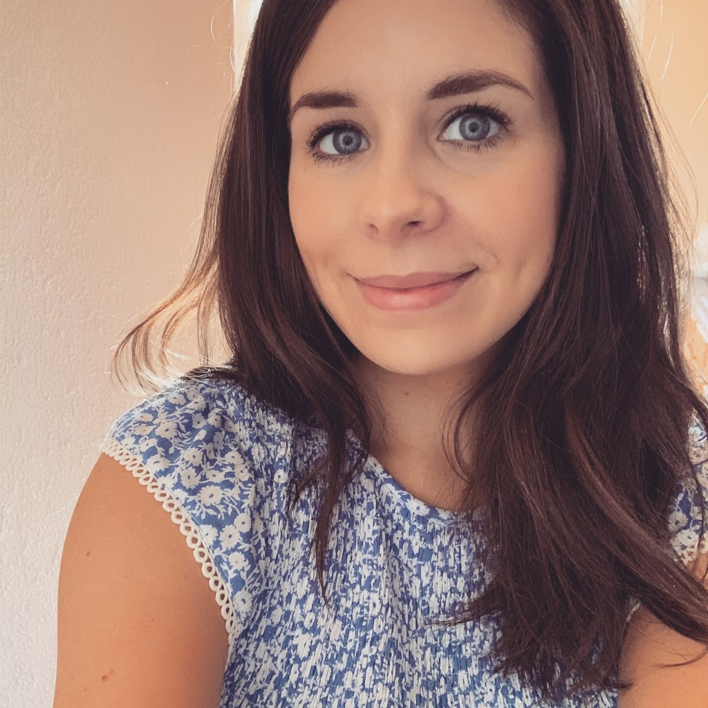 A brunette woman in a blue and white dress, smiling